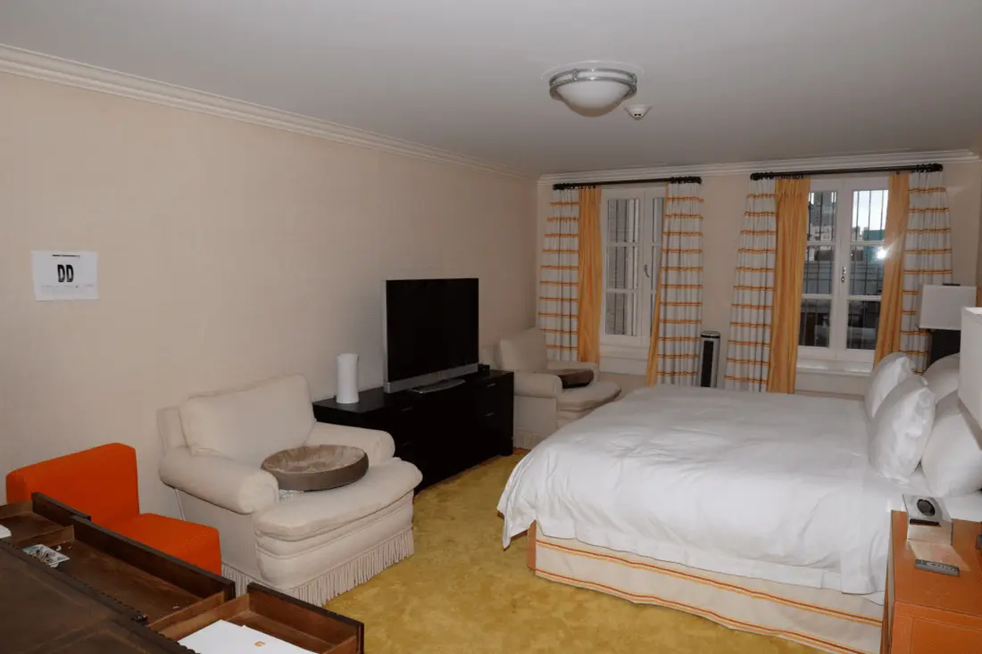 Well-appointed hotel room featuring a large bed armchair TV and orange accents